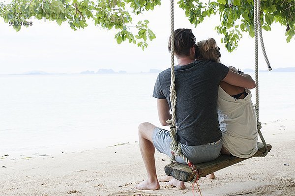 Rückansicht des jungen Paares auf der Strandschaukel  Kradan  Thailand