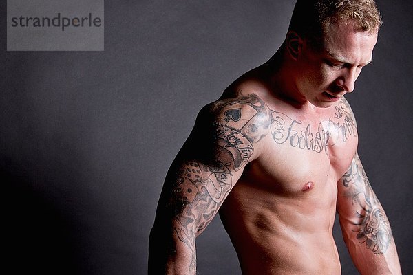 Muskulöser junger Mann mit Tattoos