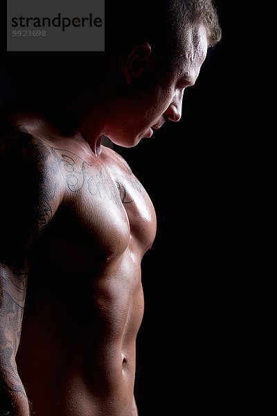Muskulöser junger Mann beleuchtet