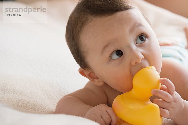 Baby Junge kaut auf Badespielzeug