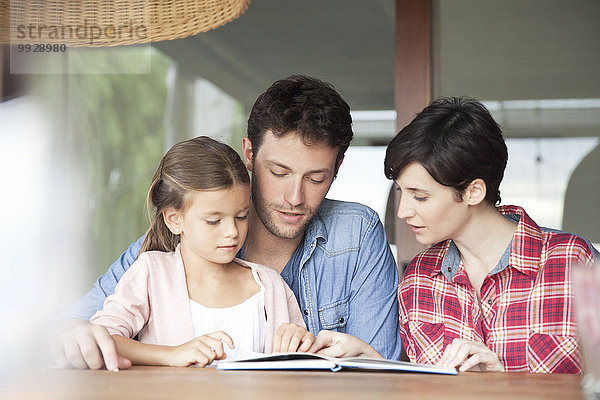 Kleines Mädchen beim Lesen mit ihren Eltern