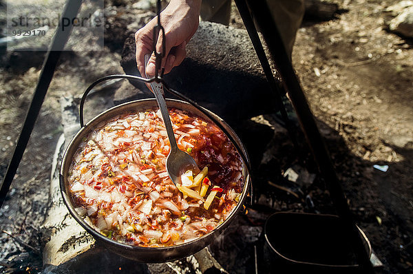 Lagerfeuer kochen über Mensch Close-up rühren Suppe