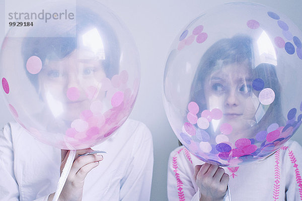Kinder verstecken sich hinter transparenten Luftballons