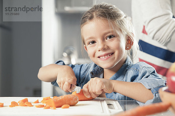 Kleines Mädchen schneidet Karotten in der Küche  Portrait