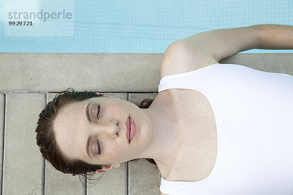 Junge Frau beim Sonnenbaden am Pool mit geschlossenen Augen  Blick nach oben