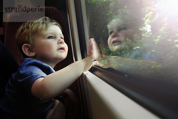 Kleiner Junge  der aus dem Zugfenster schaut.