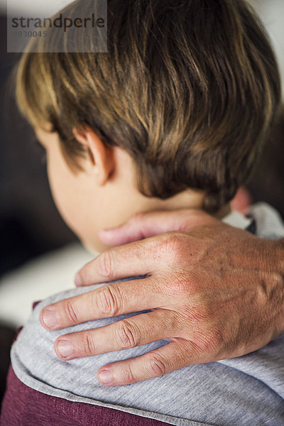 Vaters Hand auf der Schulter des kleinen Jungen  abgeschnitten