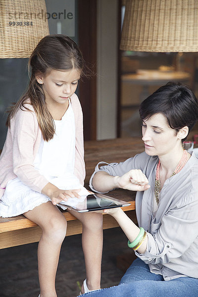 Mutter und kleine Tochter benutzen gemeinsam ein digitales Tablett.