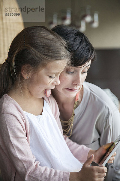 Mutter und Tochter mit digitalem Tablett und lustigen Gesichtern