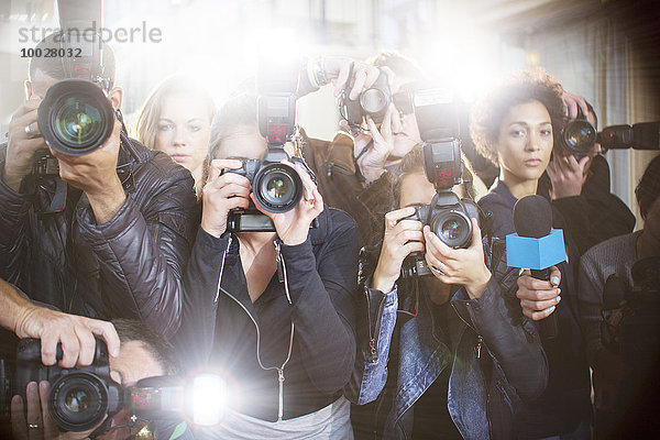 Porträt seriöser Paparazzi-Fotografen  die auf Kameras zeigen