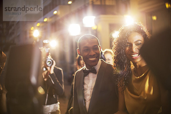 Lächelndes Promi-Paar wird von Paparazzi bei der Veranstaltung fotografiert
