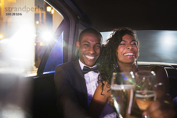 Lachendes Promi-Paar trinkt Champagner in der Limousine beim Red Carpet Event
