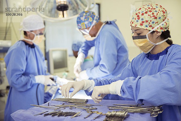 Chirurg am Tablett der chirurgischen Schere im Operationssaal