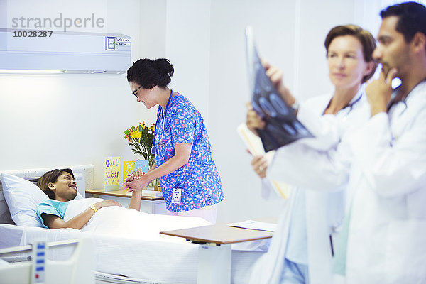 Krankenschwester hält Händchen mit Patientin im Krankenhauszimmer