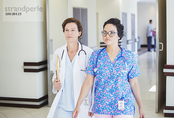 Arzt und Krankenschwester gehen gemeinsam auf dem Krankenhausflur spazieren