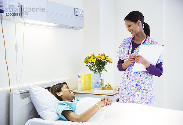 Krankenschwester im Gespräch mit Patientin im Krankenhauszimmer