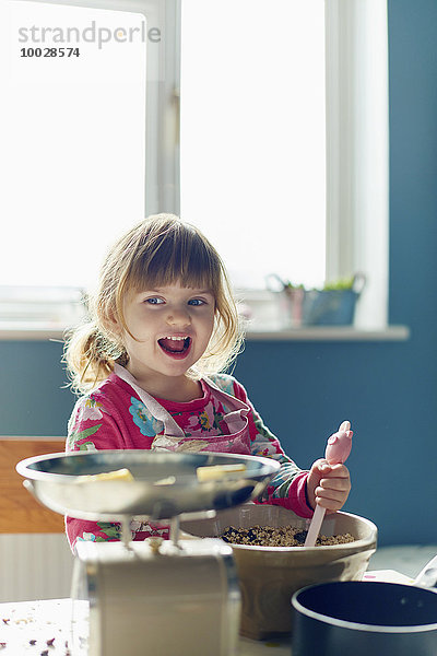 Lächelndes Mädchen beim Backen mit Rührschüssel in der Küche