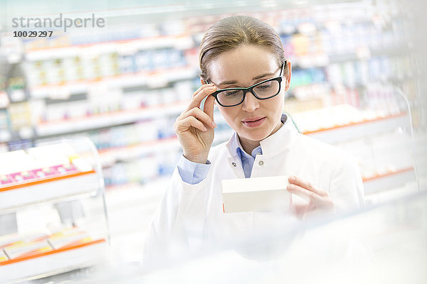 Apotheker lesen Etikett auf Karton in der Apotheke