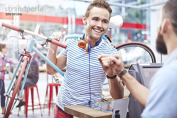 Mann mit Fahrrad-Fauststoßer im Cafe