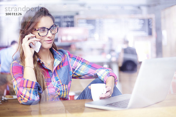 Frau mit Laptop und Telefonieren im Café