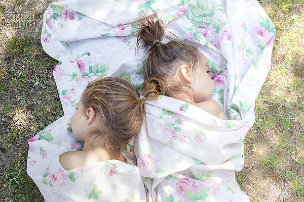 Zwillingsmädchen schlafend im Blumentuch auf Gras