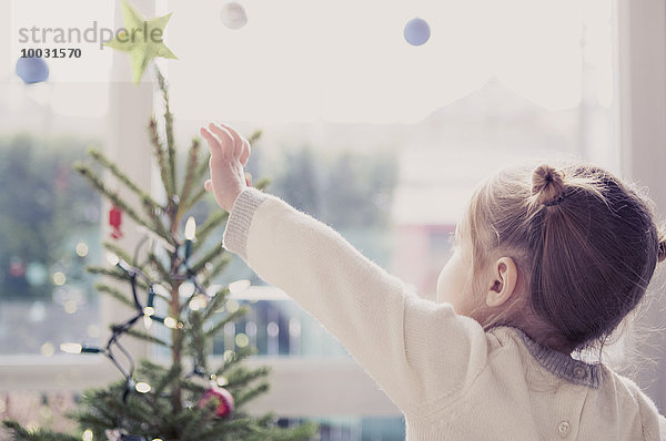 Mädchen greift nach dem Start am Weihnachtsbaum