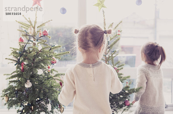 Mädchen schmücken kleine Weihnachtsbäume