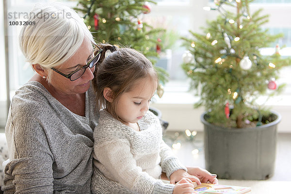 Großmutter beim Zeichnen der Enkelin vor den Weihnachtsbäumen