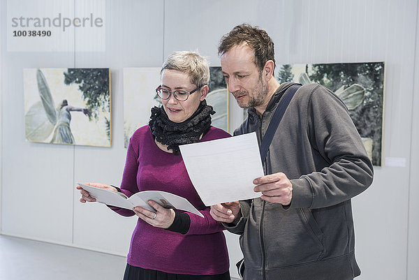 Visitors looking at brochures in an art gallery  Bavaria  Germany