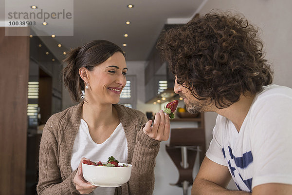 Mid adult woman feeding a strawberry to her husband  Munich  Bavaria  Germany