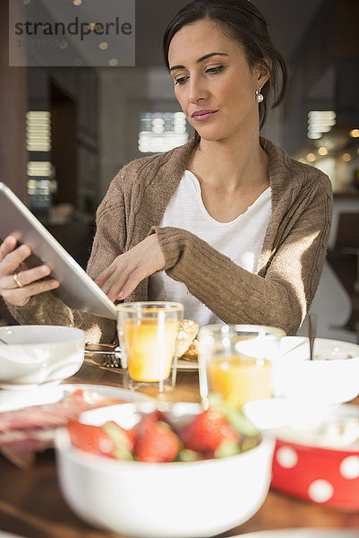 Mid adult woman using a digital table at breakfast table  Munich  Bavaria  Germany