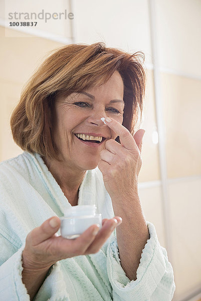Senior woman applying moisturizer on her face  Munich  Bavaria  Germany