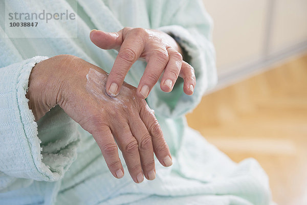 Senior woman applying moisturizer on her hand  Munich  Bavaria  Germany