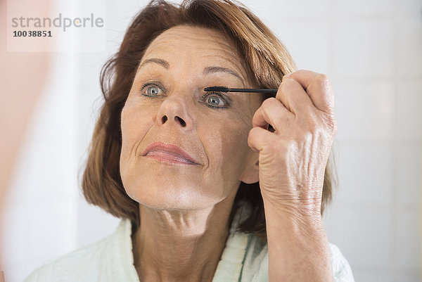 Senior woman applying eye make up with mascara  Munich  Bavaria  Germany