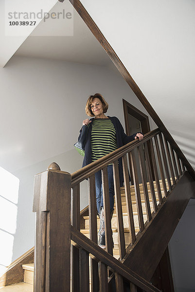 Senior woman wearing winter coat moving down on a staircase  Munich  Bavaria  Germany