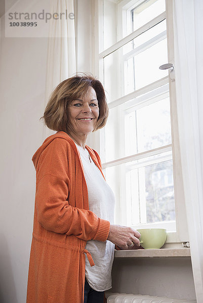 Side profile of senior woman smiling with having cup of tea at home  Munich  Bavaria  Germany