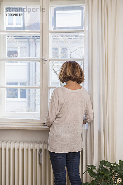 Rear view of senior woman looking through a window  Munich  Bavaria  Germany