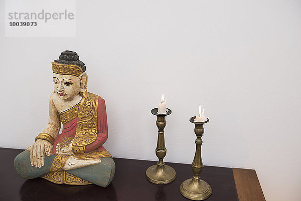 Buddha statue in lotus position with two candles  Munich  Bavaria  Germany