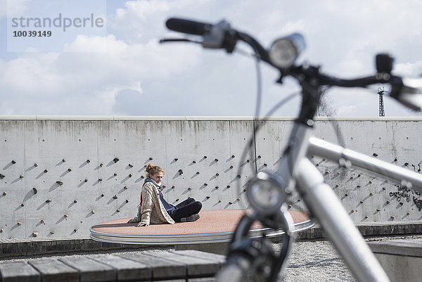 Young woman in theme park with bike in foreground  Munich  Bavaria  Germany