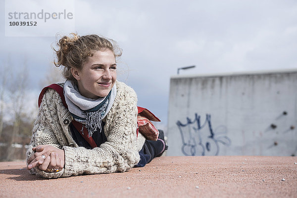 Portrait of a young woman lying on roundabout and smiling  Munich  Bavaria  Germany