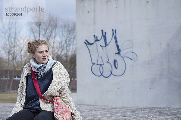 Young woman sitting on bench and waiting  Munich  Bavaria  Germany