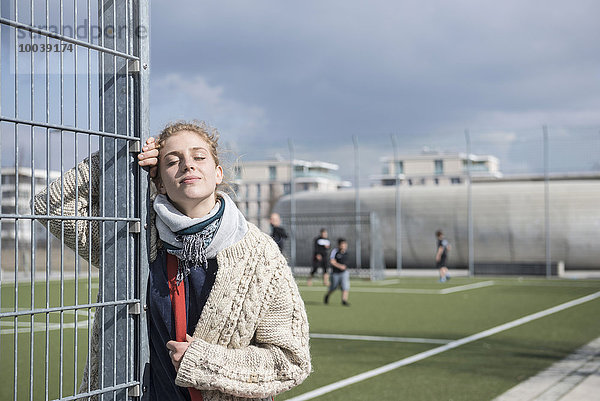 Young woman leaning on metal fence with eyes closed  Munich  Bavaria  Germany