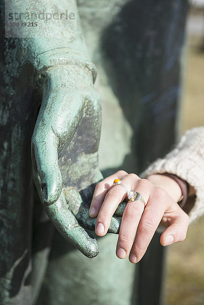 Woman touching hand of bronze sculpture  Munich  Bavaria  Germany