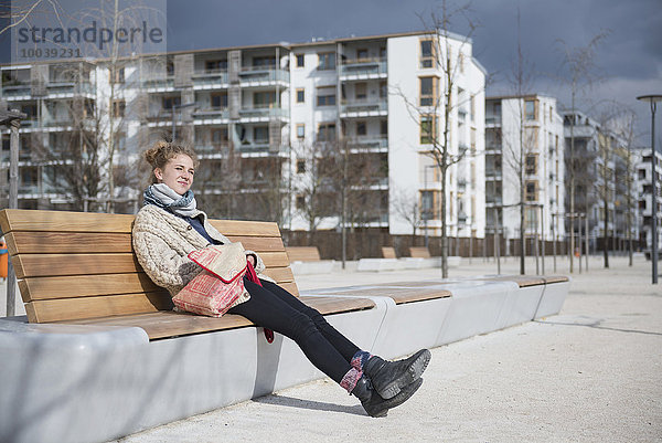 Young woman sitting on bench in city  Munich  Bavaria  Germany