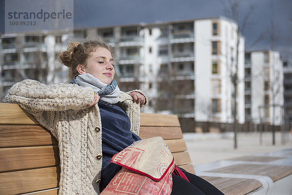 Young woman sitting on bench in city  Munich  Bavaria  Germany