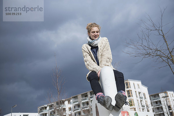 Low angle view of a young woman sitting on wall  Munich  Bavaria  Germany