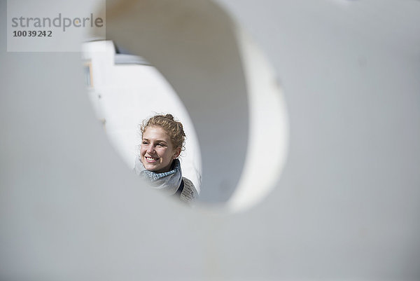 Young woman seen through a round hole in concrete wall  Munich  Bavaria  Germany