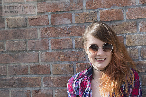 Young woman leaning in front of brick wall  Munich  Bavaria  Germany