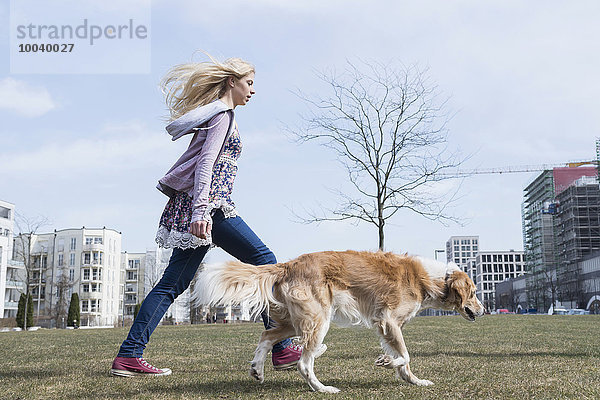 Side profile of teenage girl walking in park with dog  Munich  Bavaria  Germany