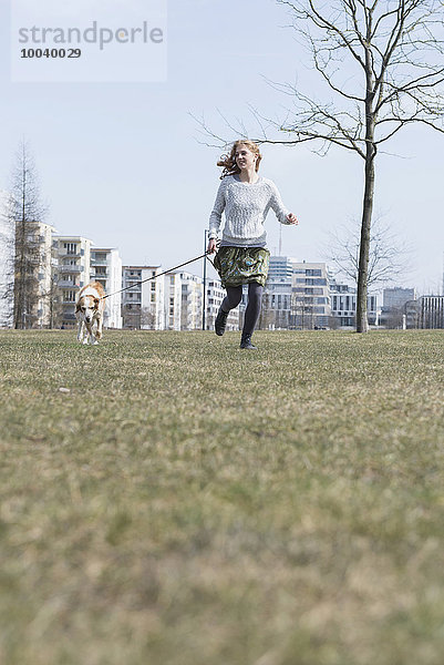 Young woman running in park with dog  Munich  Bavaria  Germany